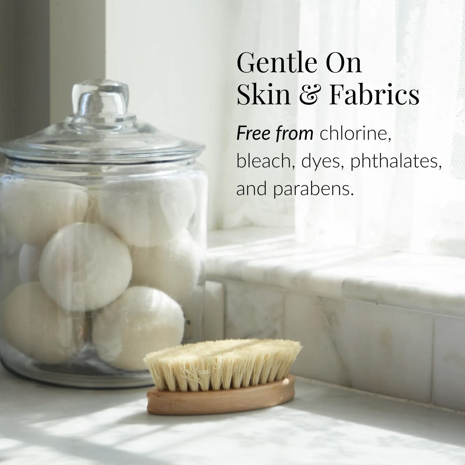 A glass jar of white wool dryer balls sits by a brush. Text reads: Gentle on Skin & Fabrics. Classic Laundry Detergent is free from chlorine, bleach, dyes, phthalates, parabens, and plant-based detergent residues. - image 4