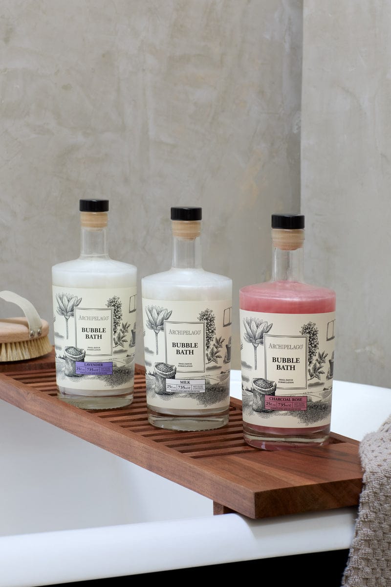 Three Archipelago 25 oz. Bubble Baths sitting on a bath tub.