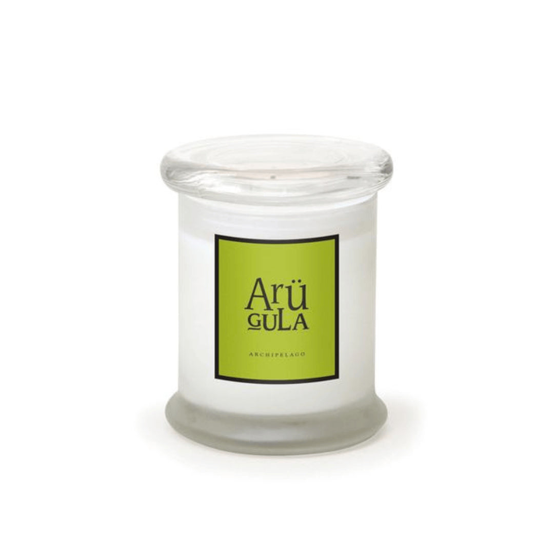 The Arugula Frosted Jar Candle is a white, hand-poured candle in a clear glass jar with a flat lid. Its label reads “Arü GULA” in black on bright green, with “ARCHIPELAGO” below, all set against a plain white background.1