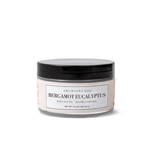 A clear jar with a black lid labeled Bergamot Eucalyptus Body Butter, 7 fl oz (207 ml), sits against a white background, offering plant-based hydration for your skin.