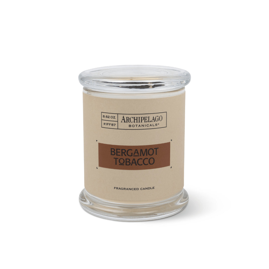 The Bergamot Tobacco Jar Candle features Italian Bergamot and Tobacco Flower notes. Made with premium soy wax, it comes in a clear glass jar with a beige and brown label and matching lid by Archipelago Botanicals.1