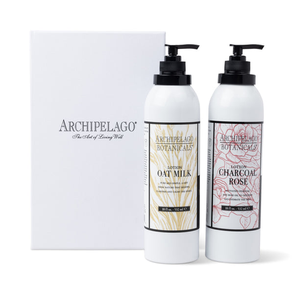 Two white pump bottles from the Best Selling Luxury Lotion Gift Set—one Oat Milk Lotion and one Charcoal Rose Lotion—stand before a white gift box featuring elegant black text.