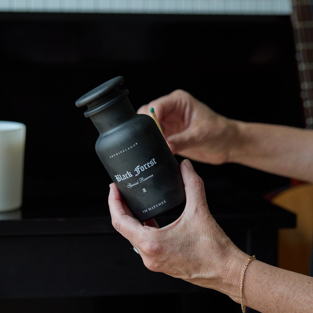 Person holding a black bottle labeled 'Black Forest' with a blurred background2