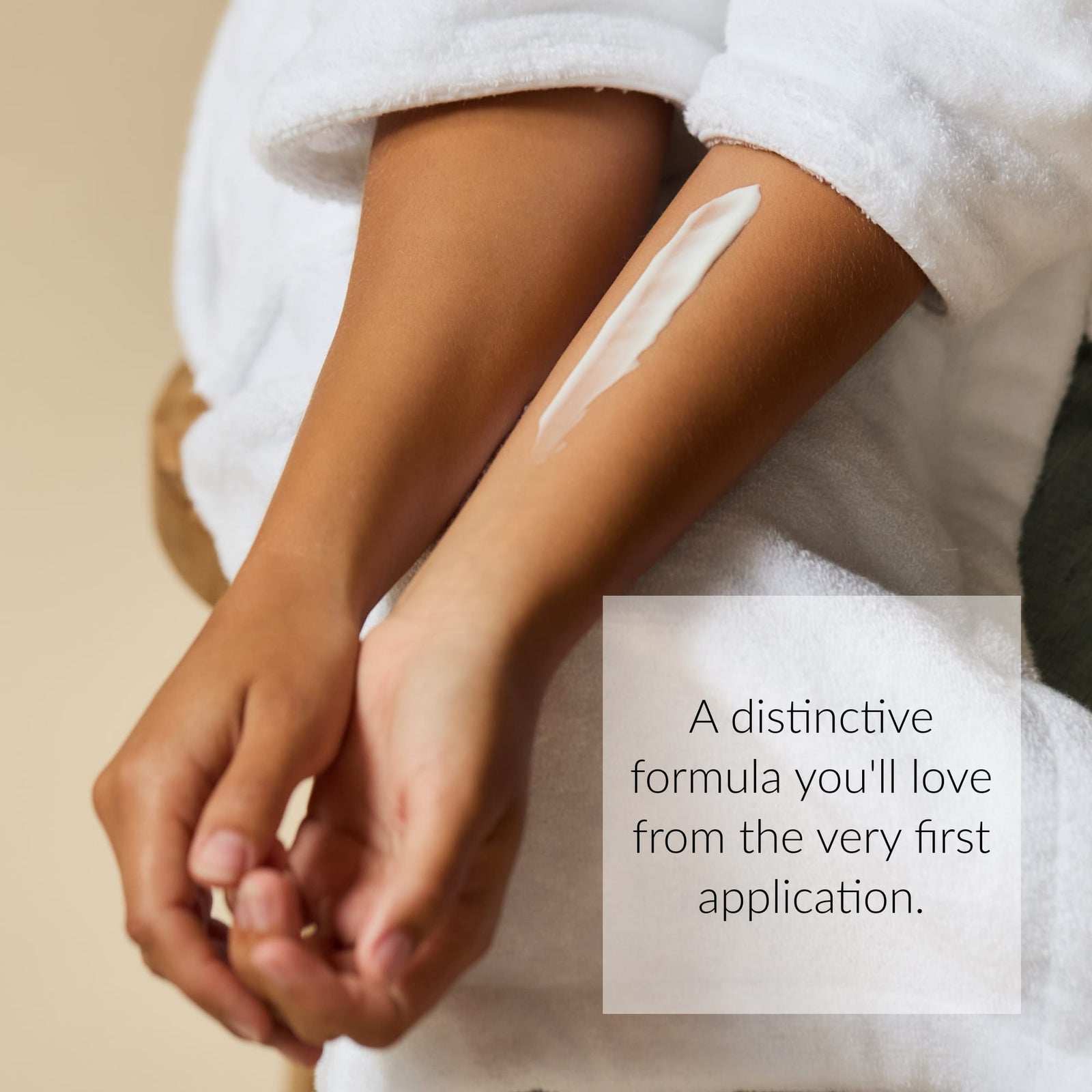 A person in a white robe applies a streak of Black Honey Body Lotion on their forearm. A text overlay reads, A distinctive formula you’ll love from the very first application.5
