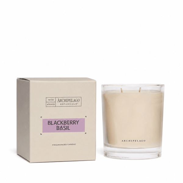A hand-poured Blackberry Basil Credenza Candle sits beside its light beige box with a purple label, reading Archipelago Botanicals, Blackberry Basil, Fragranced Candle. The premium wax blend comes in this elegant packaging.