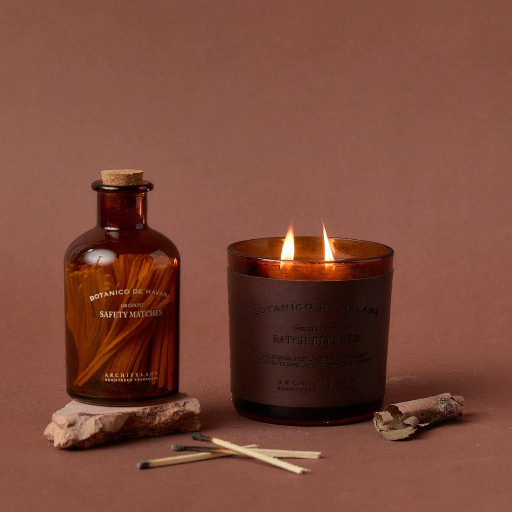 A bottle of Botanico de Havana Matches next to a lit candle.