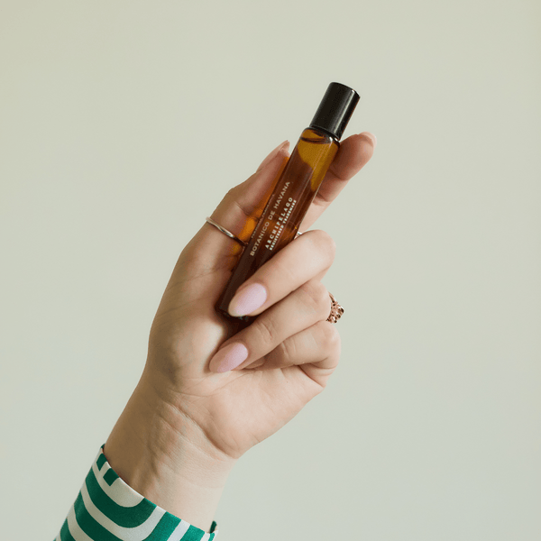 Hand holding fragrance roller bottle on light background