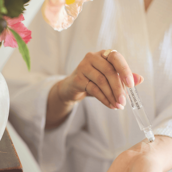 Hand holding perfume roller bottle on light background 