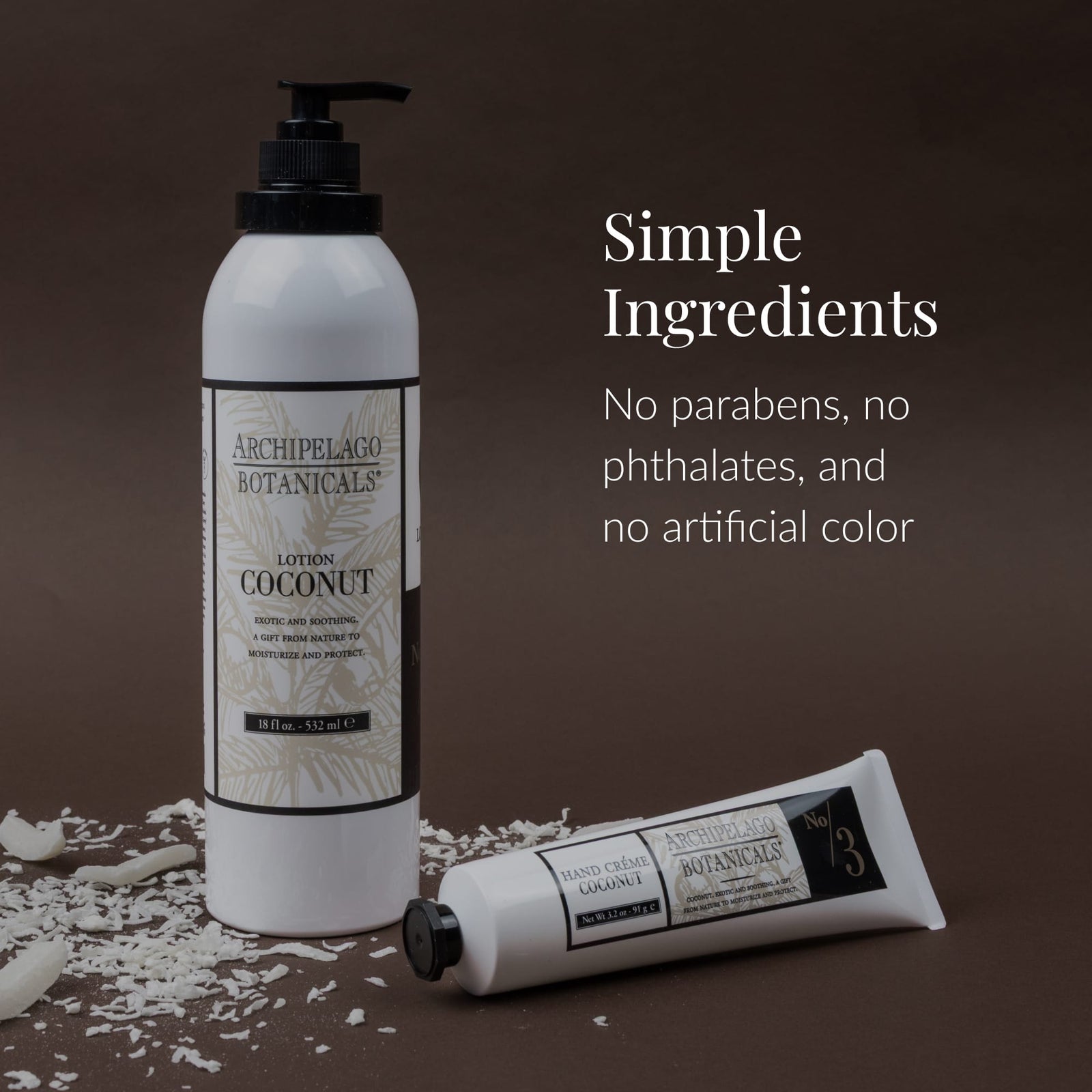 Two white bottles of Coconut Body Lotion by Archipelago Botanicals rest on a brown background scattered with coconut flakes. Text: Simple Ingredients. Infused with Coconut Oil and Jojoba Esters. Free from parabens, phthalates, and artificial colors.2