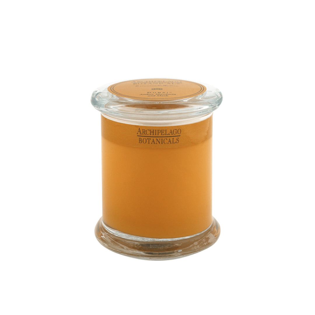 The Dubai Jar Candle features amber-colored wax in a glass jar with a lid and is labeled Archipelago Botanicals—perfect for creating an inviting home fragrance in any space.1