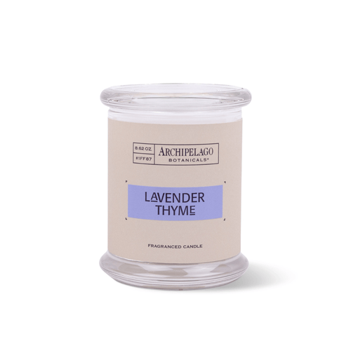 The Lavender Thyme Jar Candle is a clear glass soy wax candle with a beige label featuring a purple scent name. This white French Lavender candle offers an essential oil fragrance.