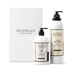Two white bottles—Milk Body Wash and Oat Milk Body Lotion—stand in front of a gift box with the Archipelago logo and wheat designs, featured as the Oat Milk Daily Ritual Gift Set. - image 1
