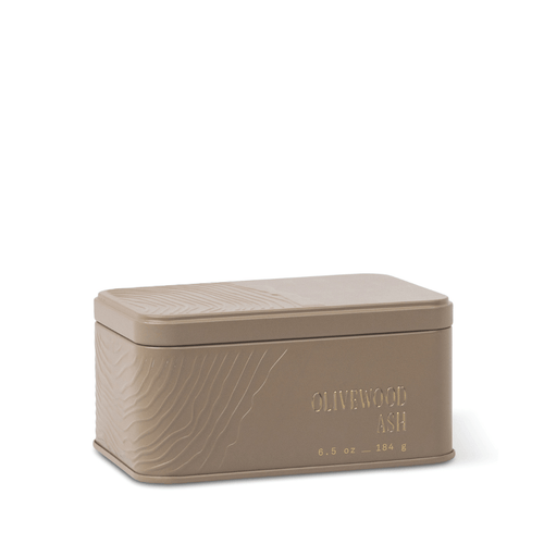 Introducing the Olivewood Ash Travel Tin Candle: a rectangular taupe tin featuring textured lines and “OLIVEWOOD ASH” embossed on the front, along with its weight—6.5 oz (184 g). The smooth lid, finished in a matching taupe hue, beautifully complements the understated mineral fragrance inside.