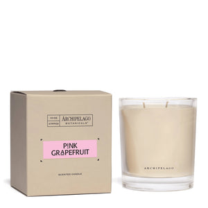 A beige box labeled Pink Grapefruit Credenza Candle stands beside a clear glass candle with off-white wax and two wicks. The simple, elegant packaging complements the candle’s fresh design.1