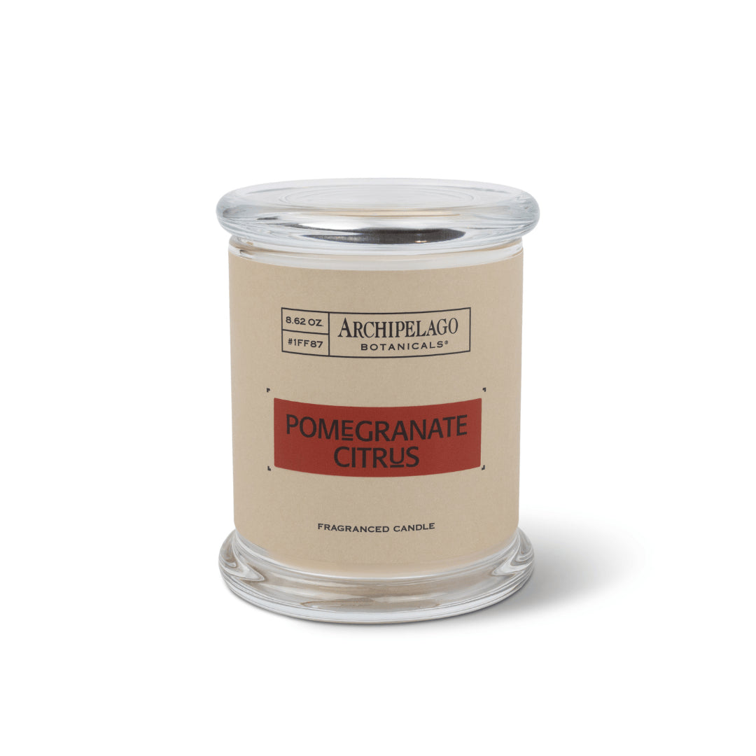 The Pomegranate Citrus Jar Candle is a clear glass jar candle with a beige label. Made from a soy-wax blend, it features a round glass lid and is shown on a white background.1
