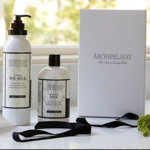Soy Milk Body Lotion by Archipelago Botanicals is beautifully displayed with a matching body wash in a white gift box finished with a black ribbon on a sunlit windowsill. This paraben free lotion, enriched with nourishing soy protein, offers a luxurious self-care experience.7