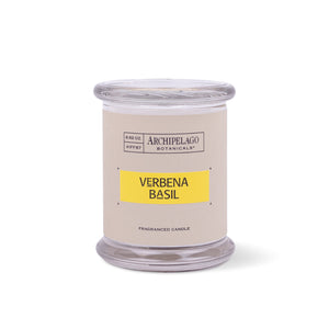 A clear glass jar candle with a beige label that reads "Archipelago Botanicals, Verbena Basil, Fragranced Candle." The label features a yellow section to highlight the scent on this elegant Verbena Basil Jar Candle.1