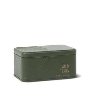 Rectangular green metal tin with embossed patterns and “WILD TERRA” along with “6.5 oz – 184 g” printed in gold on the front. The Wild Terra Travel Tin Candle features a fitted lid and sits on a white background, making it perfect for enjoying a portable fragrance wherever you go. - image 1