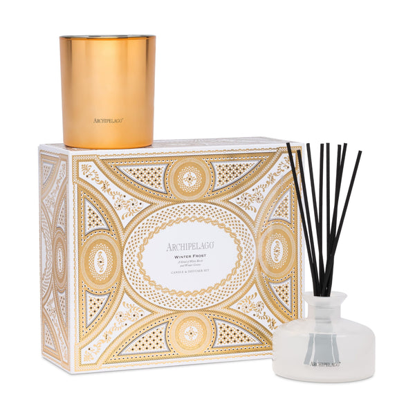 The Winter Frost Candle & Diffuser Gift Set includes a gold candle, a glass reed diffuser with black reeds, and a white and gold decorative box.