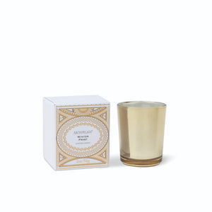 A square white box with gold decorative filigree next to a small metallic gold Winter Frost Petite Candle glass. - image 1